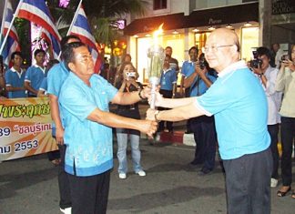 Wattana Chantanawaranon, Deputy Mayor of Pattaya City, receives the auspicious National Games torch from a representative of the Takhiantia Municipality on Monday, December 7 at Bali Hai Pier, Pattaya.