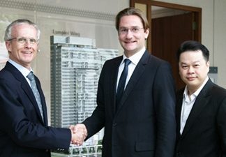 Bouygues Thai Managing Director Jean-Marie Verbrugghe, left, shakes hands with Raimon Land’s Chief Executive Officer Hubert Viriot, center, as Raimon Land Chief Operating Officer Kitti TungSriwong looks on.