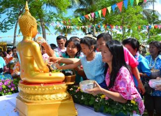 Young and old gather to pour lustral water on the Buddha.