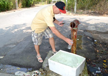 Roy Albiston uses a water bottle and calculator to evaluate the water being lost from this emergency water pipe that has been leaking for 4 years.