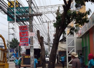 Pattaya Engineering Department workers cut trees and branches away from utility wires in front of Rattanakorn Market.