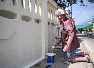 Briton Terry Smith takes a break from painting the wall at Sutthawat Temple to smile for a photo.