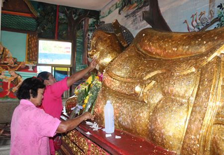 People place gold leaf on the reclining Buddha image at Suthawas temple in Nongprue.