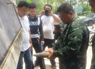 Police and military personnel inspect the old and rusted ordinance.