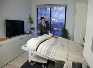 Stage 3 Properties co-founder Christopher Bledsoe demonstrates a retractable bed that turns into a sofa when stored inside one of the apartment units at the Carmel Place building in New York City. (AP Photo/Julie Jacobson)