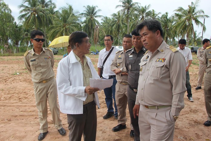 Former chairman of the Pattaya City Council Tavich Chaiswangwong (left, wearing white jacket) explains the history behind the barrels disposed on his land.