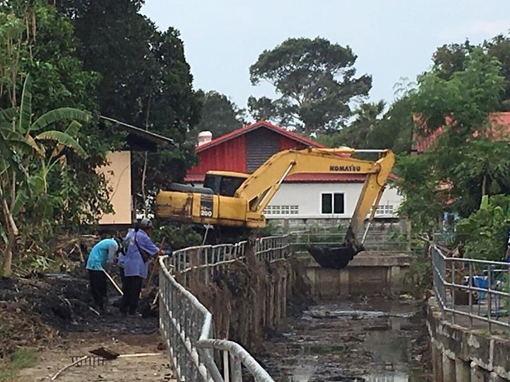 A team of workers with a backhoe dredge weeds and garbage from Naklua’s Nokyang Canal.