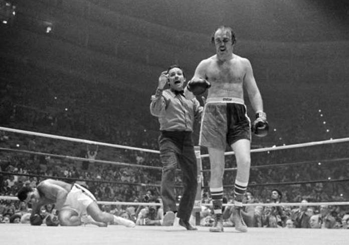 Tony Perez sends Chuck Wepner to a neutral corner as heavyweight champion Muhammad Ali (left) starts to get to his feet during the ninth round of their title bout at the Cleveland Coliseum in Richfield, Ohio, March 24, 1975. (AP Photo/Charles Knoblock)