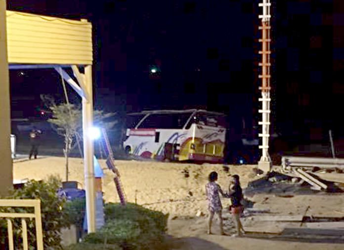 Bystanders look on as rescue workers attempt to recover a tour bus which crashed into the sea in north Pattaya on Tuesday evening.