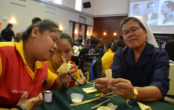 Sister Pavinee, from the Vocational School, shows her students the art of flower making.