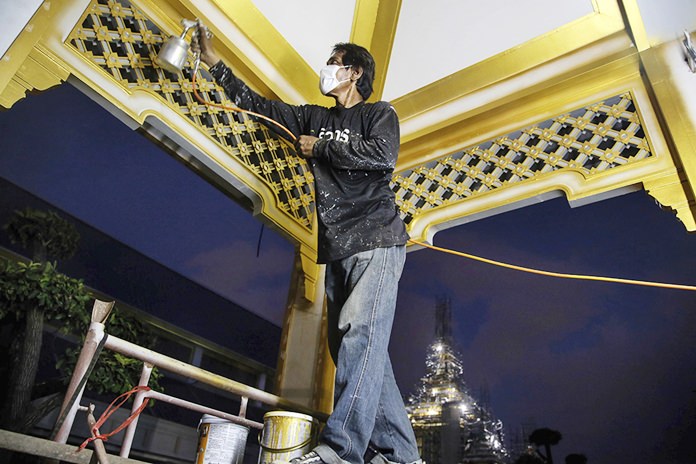 A worker paints the roof of one of the buildings at the royal crematorium in Sanam Luang.