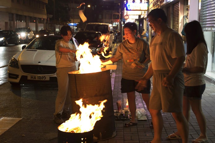 A family burns paper money – locally known as “Hell Money” – during the “Hungry Ghost Festival” on a street in Hong Kong. (AP Photo/Kin Cheung)