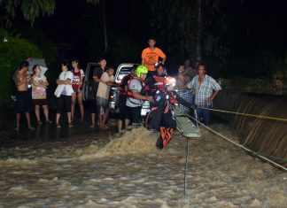 Two teams of paramedics use ropes to pull two men to shore after their SUV was swept off a river road in Khao Maikaew.