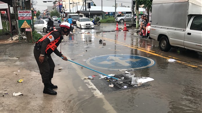 Police volunteer Prasert Tienyi attempts to clear debris from a drain on Soi Khao Noi during a heavy rainstorm, Oct. 9.