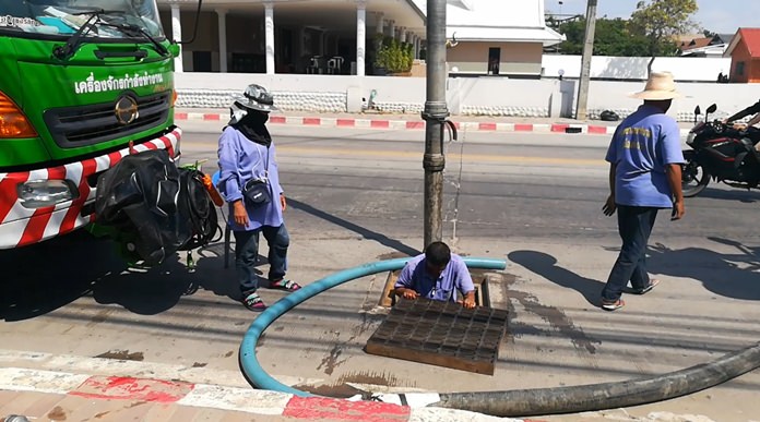 Pattaya sanitation workers clean out drains along Beach Road to mitigate flooding.