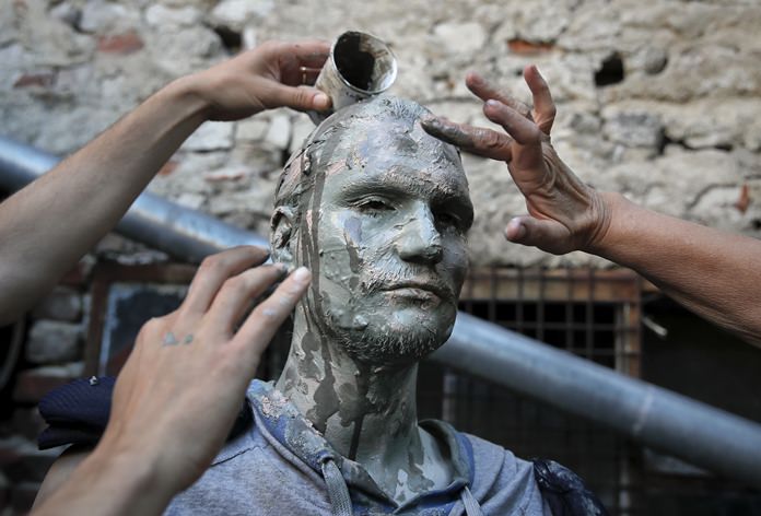 An artist of Romania’s Masca theatre has make-up applied to his face before performing at the Living Statues International Festival, in Bucharest. (AP Photo/Vadim Ghirda)