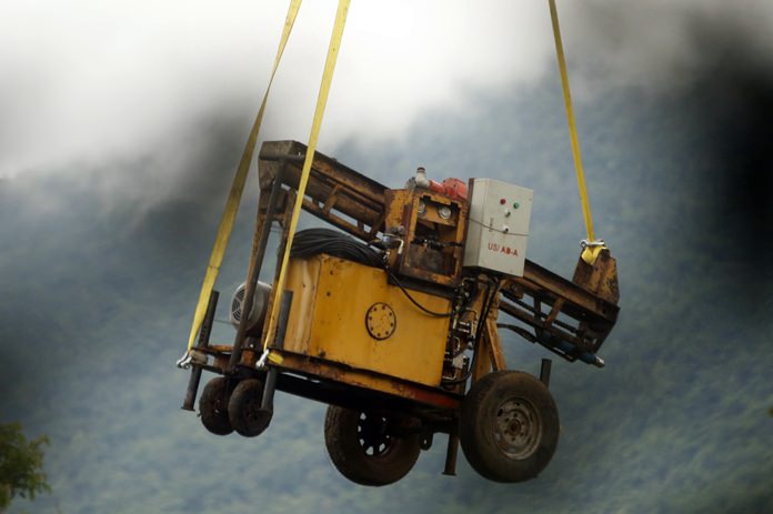 A military transport helicopter carries a drill machine to be used for the rescue search of missing 12 boys and their soccer coach, in Mae Sai, Chiang Rai province, in northern Thailand, Monday, July 2, 2018. (AP Photo/Sakchai Lalit)