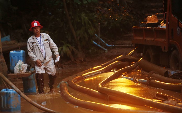 A rescuer makes his way down muddy steps past water pump hoses at the entrance to a cave complex where 12 soccer team members and their coach went missing, Monday, July 2, 2018, in Mae Sai, Chiang Rai province, in northern Thailand. (AP Photo/Sakchai Lalit)