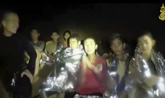 In this July 3, 2018, image taken from video provided by the Thai Navy Seal, Thai boys are with Navy SEALs inside the cave, Mae Sai, northern Thailand. With heavy rains forecast to worsen flooding in a cave in northern Thailand where 12 boys and their soccer coach are waiting to be extracted by rescuers, authorities say they might be forced to have them swim out through a narrow, underwater passage. The 13 are described as healthy and being looked after by medics inside the cave.(Thai Navy Seal via AP)