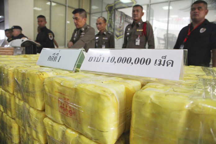 Policemen stand in front of seized methamphetamine pills at the Narcotics Suppression Bureau during a press conference in Bangkok, Tuesday, Sept. 18. (AP Photo)