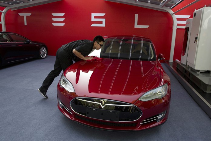 In this April 22, 2014, file photo, a worker cleans a Tesla Model S sedan before an event to deliver the first set of cars to customers in Beijing, China. (AP Photo/Ng Han Guan)
