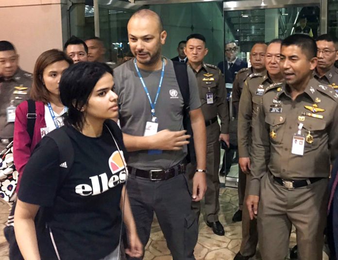 In this Jan. 7, 2019, file photo, Saudi woman Rahaf Mohammed Alqunun, foreground, walks by Chief of Immigration Police Maj. Gen. Surachate Hakparn, right, before leaving Suvarnabhumi Airport in Bangkok. (Immigration police via AP)