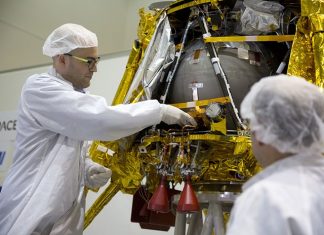 SpaceIL co-founder Yonatan Winetraub, left, inserts a time capsule into the SpaceIL lunar module, an unmanned spacecraft, that is on display in a special “clean room” where the space craft is being developed, during a press tour of their facility near Tel Aviv, Israel, Monday, Dec. 17, 2018. SpaceIL and the state-owned Israel Aerospace Industries plan to launch their unmanned spacecraft to the moon early in 2019. (AP Photo/Ariel Schalit)