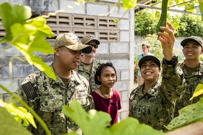 Lt. j.g. Jasmin Nicasio, from San Diego, reaches for a vegetable in the Child Protection and Development Center garden during a community service project in Chonburi.