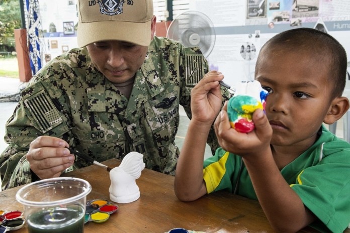 Lt. Danny Cho, from Marina, Calif., paints with a child during a community service project at the Child Protection and Development Center in Chonburi.