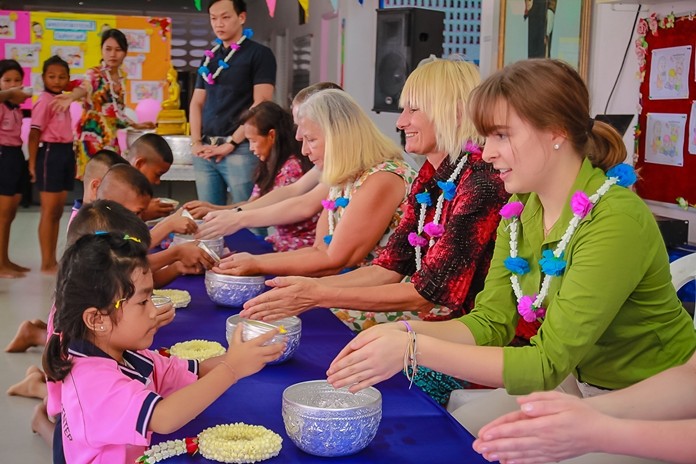 Drop-In Center children pour water on the hands of volunteers.