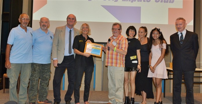 MC Bob Smith presents Pattaya Players’ Wendy Kahn, who directed the performance of “The Allotment Plot,” with the PCEC’s Certificate of Appreciation while the Players look on.