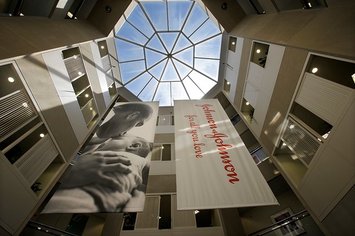 In this July 30, 2013, file photo, large banners hang in an atrium at the headquarters of Johnson & Johnson in New Brunswick, N.J. Johnson & Johnson has agreed to a $117 million multistate settlement over allegations it deceptively marketed its pelvic mesh products, which support women’s sagging pelvic organs. (AP Photo/Mel Evans, File)