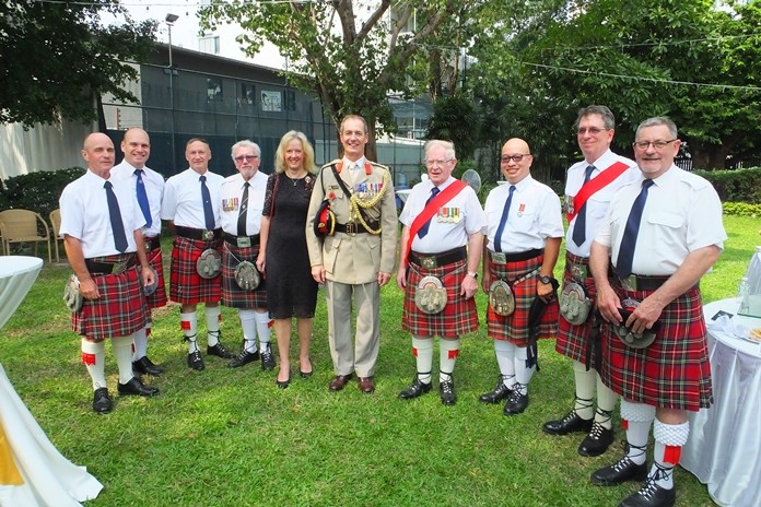 Colonel Roger and Kimberley Lewis stand with members of The British Club Pipes and Drums band.