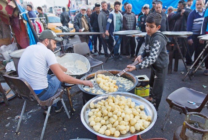 In this photo taken Sunday, Dec. 8, 2019, a volunteer chef prepares to serve free portions of the popular sweets of Awamah, fried dough balls, to protester in the center of Baghdad, Iraq. (AP Photo/Nasser Nasser)