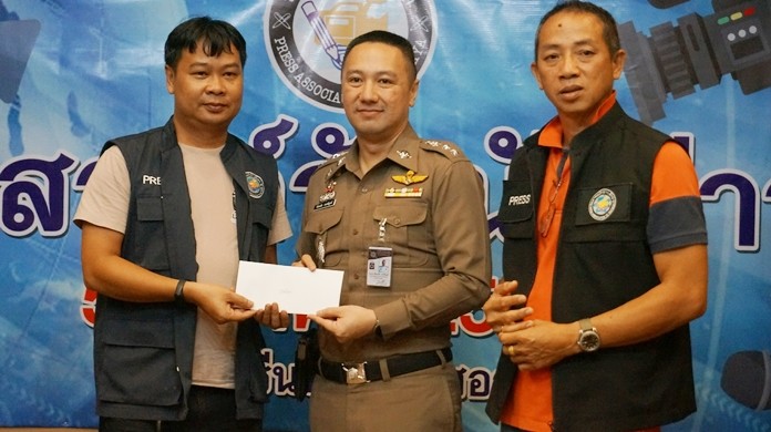 Pol. Col. Pattanachai Pamornpiboon, Banglamung Police Station Superintendent, and Samart Thongrod, President of Pattaya Press Association, present an award to Ton, reporter from BTV.