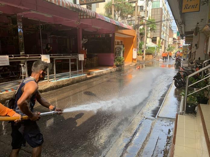 City workers use a high powered water hose down the street of dirt and dust which could harbor any viruses.