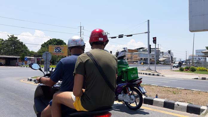 Foreign motorists look on a Grab deliveryman at central Pattaya Sukhumvit HW intersection. The number of home deliverymen in Pattaya increases rapidly amid COVID-19 outbreak