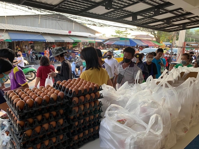 Hundreds of people walk past the distribution tables to pick up food and eggs.