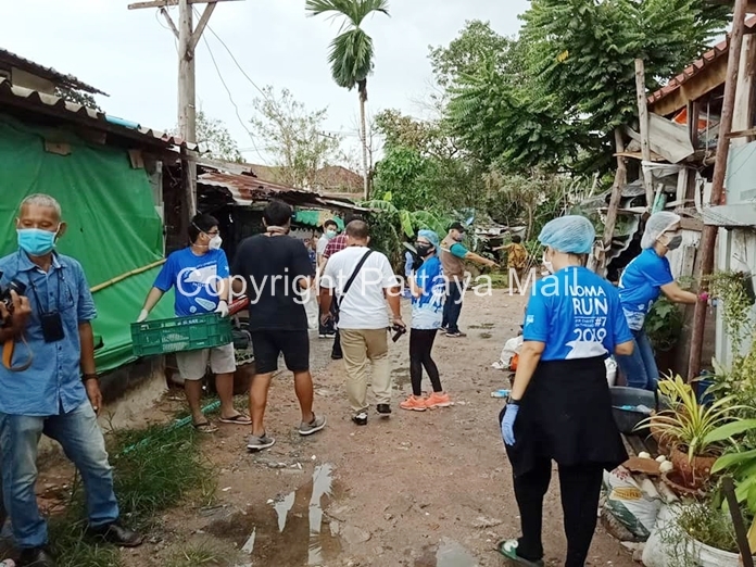 The team of volunteers go through puddles in the dirt path giving care packages to every household.